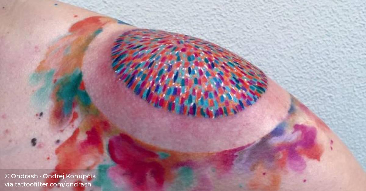 Abstract circle tattoo on the left shoulder.