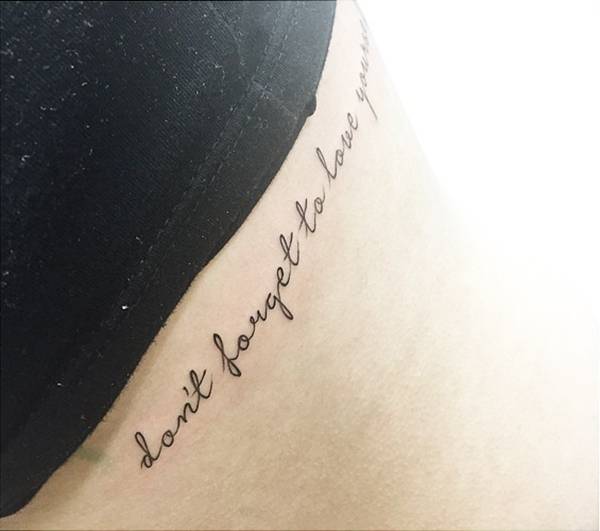 Side tattoo saying "Don't forget to love yourself".