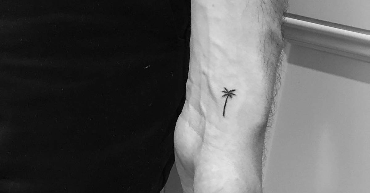 Minimalist palm tree tattoo on the left inner wrist.