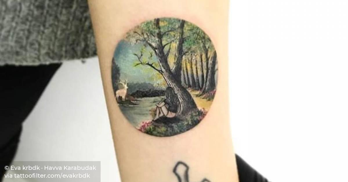 Miniature landscape circle tattoo on the inner forearm.