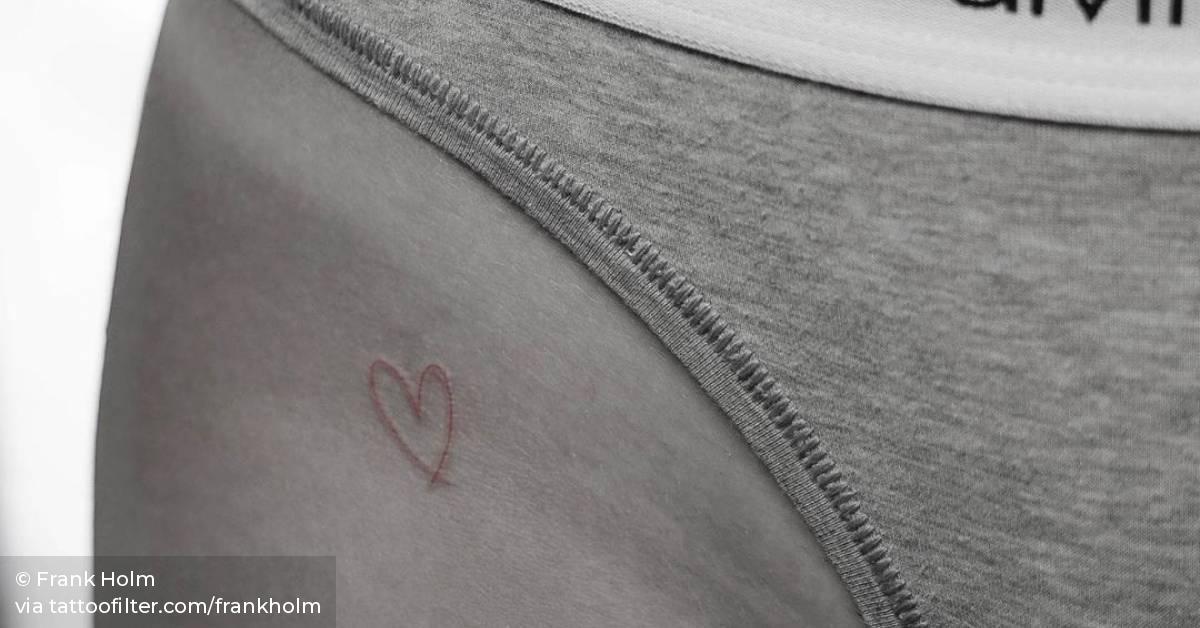 Red ink heart tattoo on the hip.