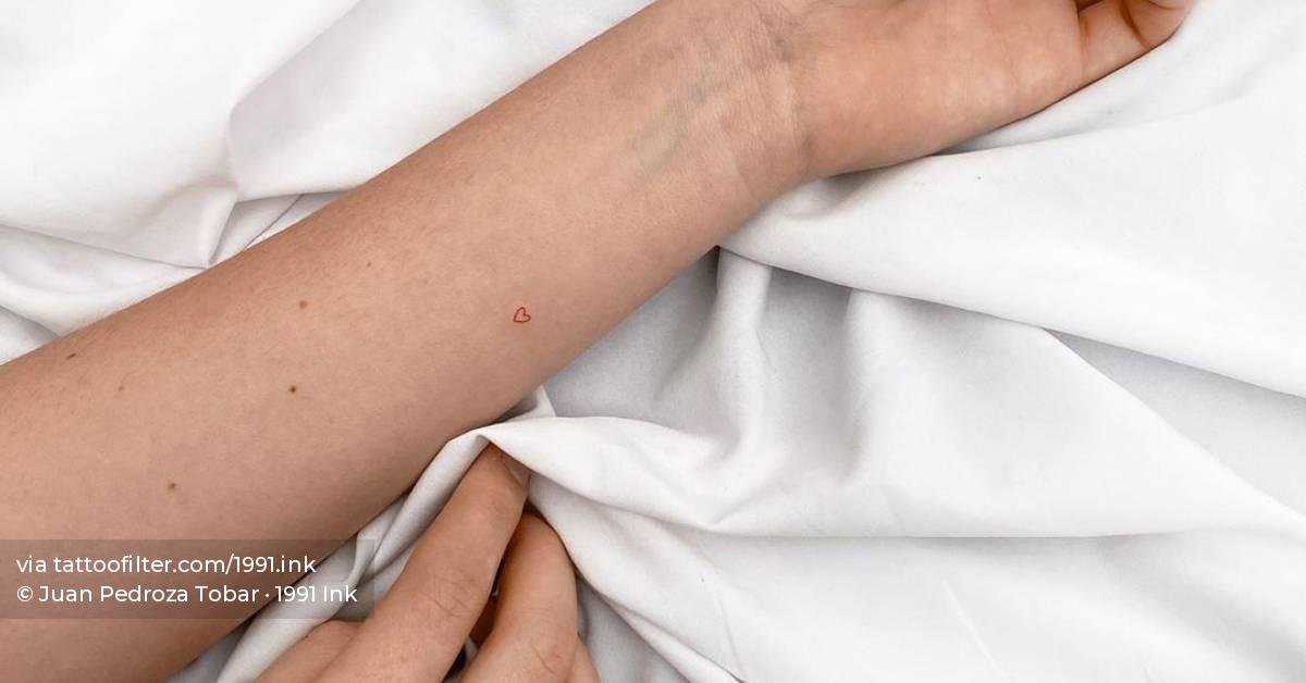Tiny red heart tattoo on the inner forearm.