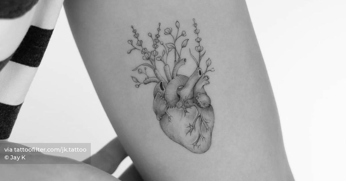 Anatomical heart with flowers tattooed on inner arm