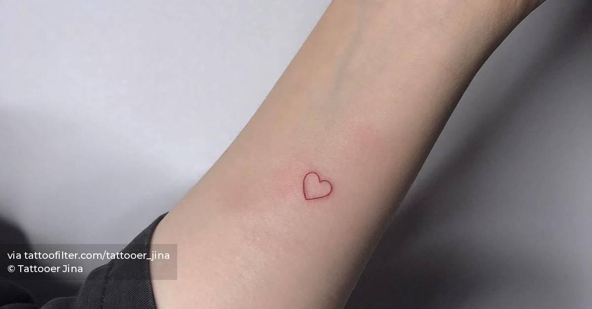 Minimalist red heart tattoo on the inner forearm