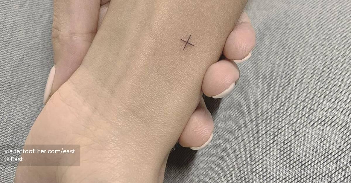 Minimalist plus sign tattoo on the wrist