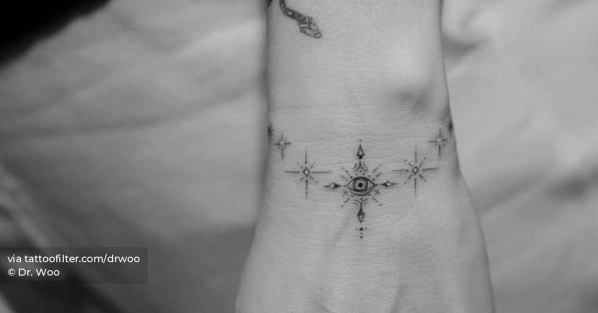 Single needle ornamental evil eye wristband tattoo