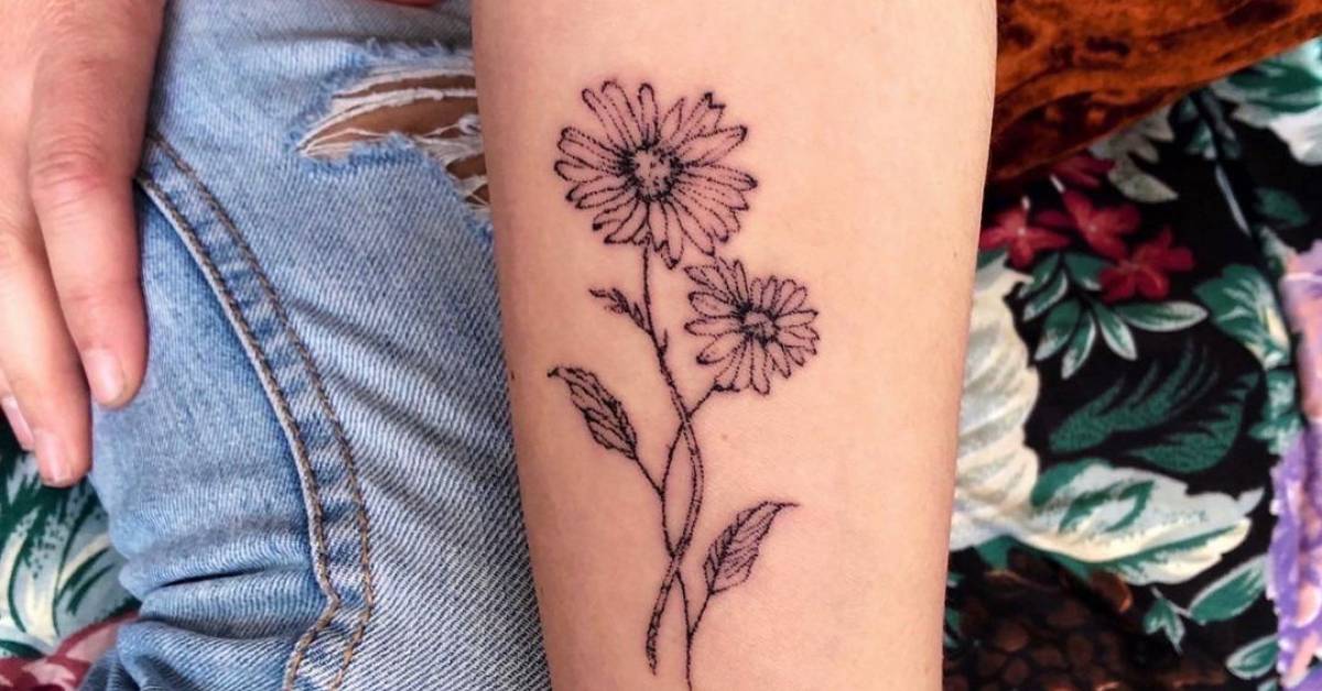 Hand poked daisy flower tattoo on the inner forearm.