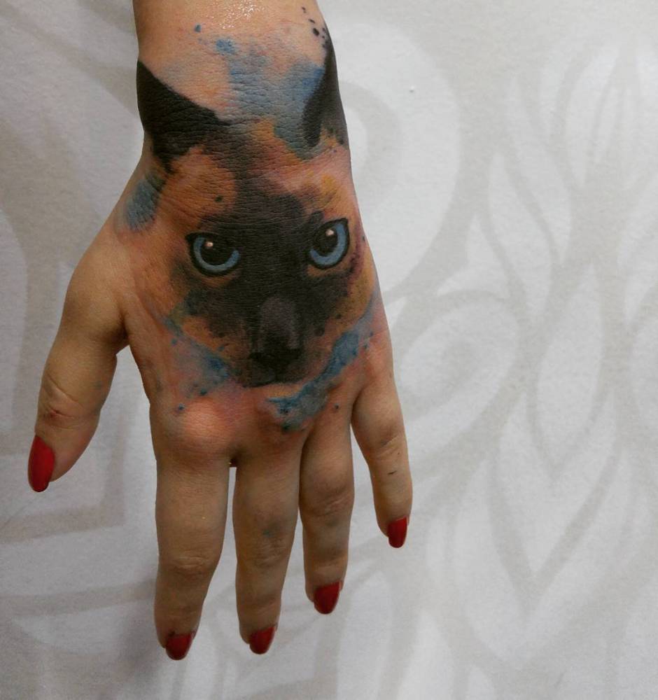 Watercolor style siamese cat tattoo on the left hand.