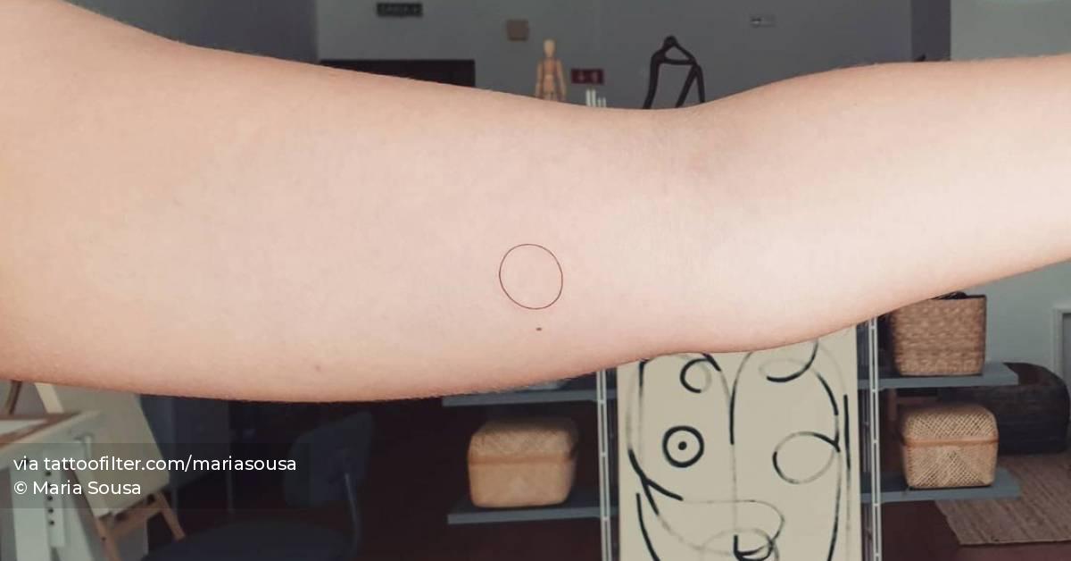 Minimalist circle tattoo on the inner arm.