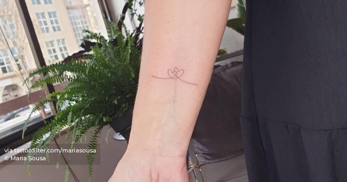 Minimalist heart tattoo on the inner forearm.
