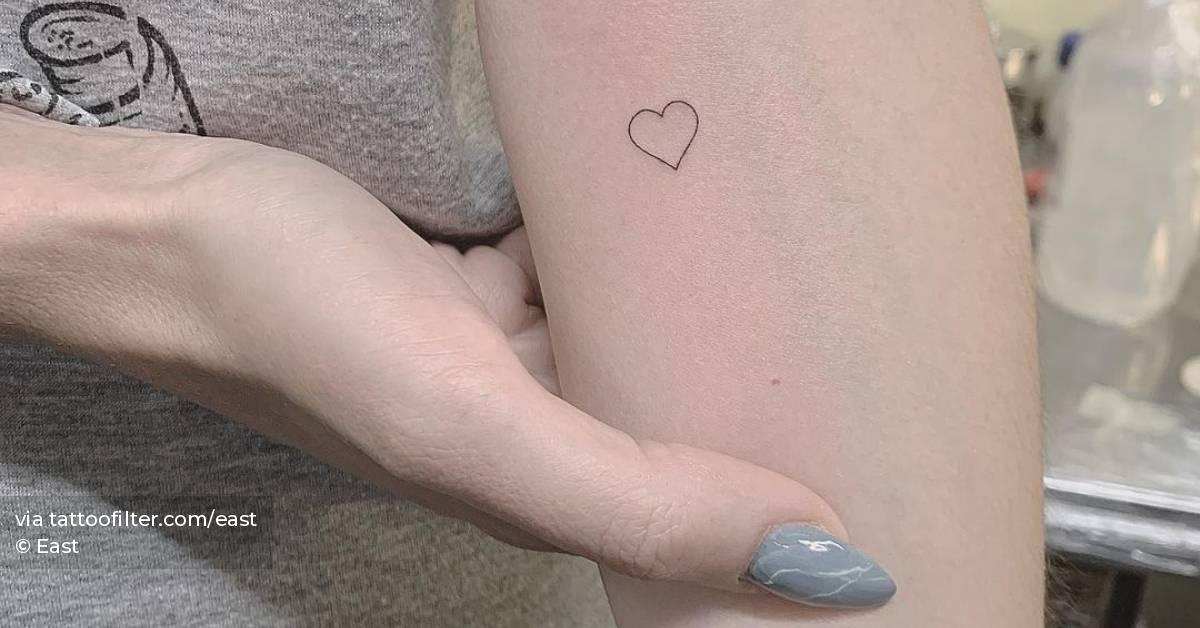 Minimalist heart tattoo on the inner forearm.