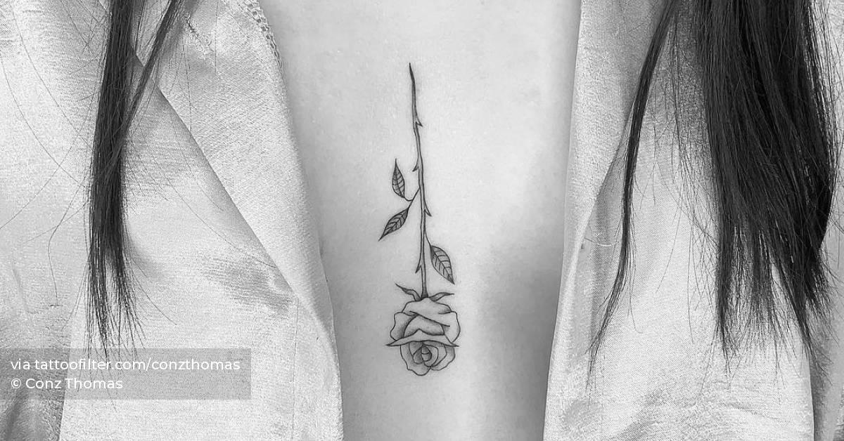 Fine line rose tattoo on the sternum.