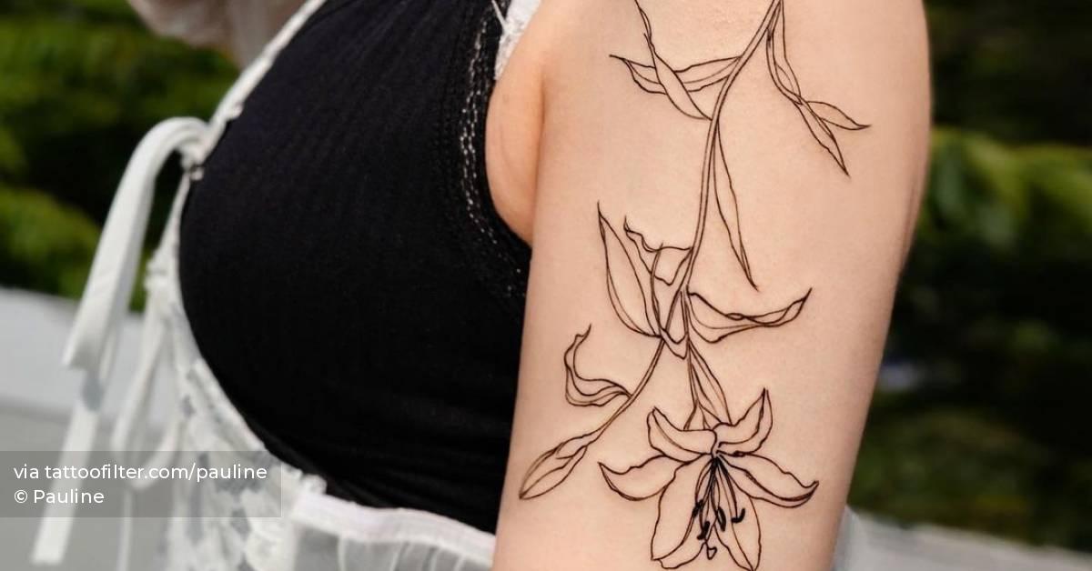 Sketch work lily flower tattoo on the upper arm.