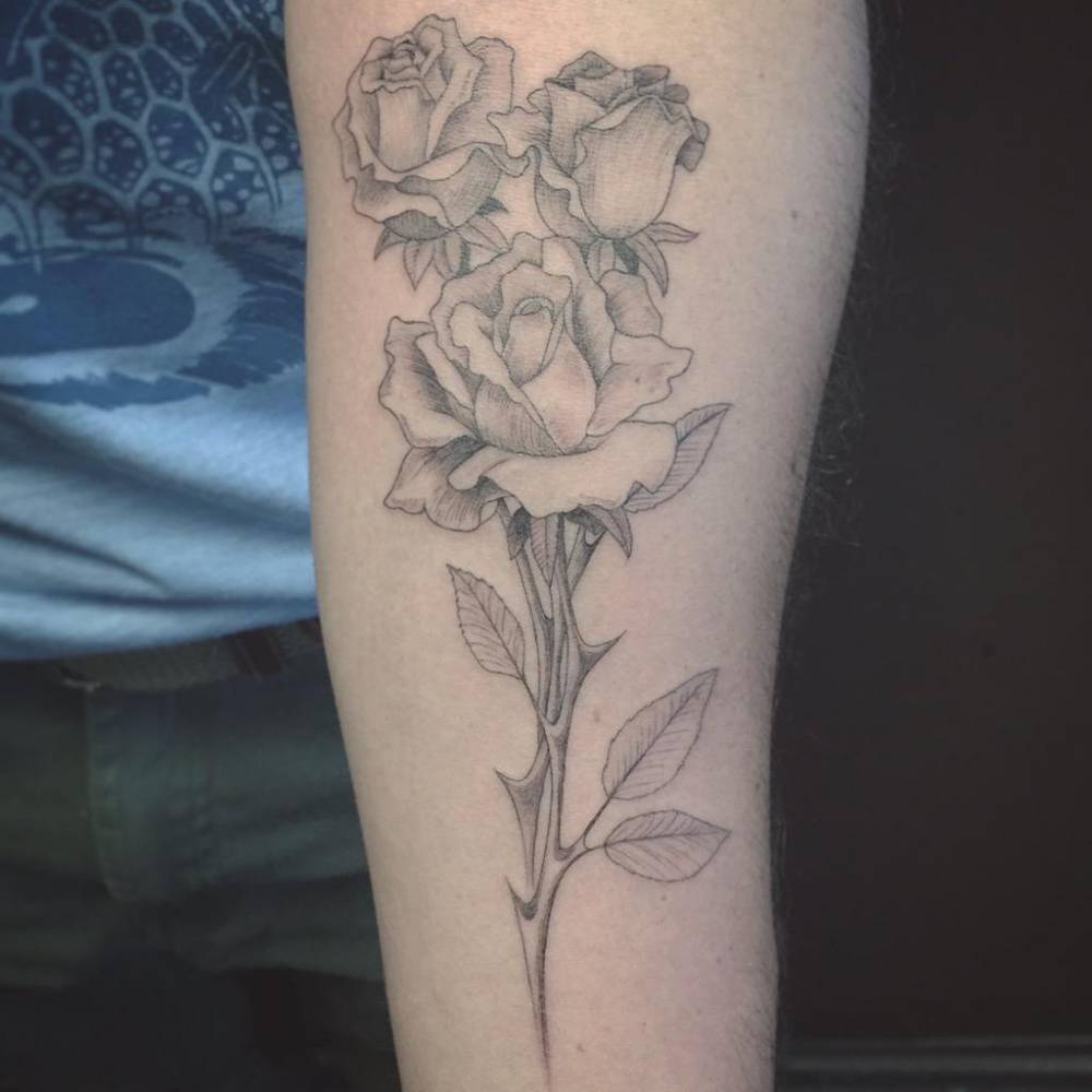 Fine line style rose on the forearm.