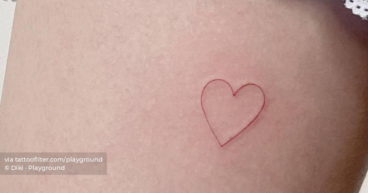 Minimalist red heart tattoo on the inner arm.