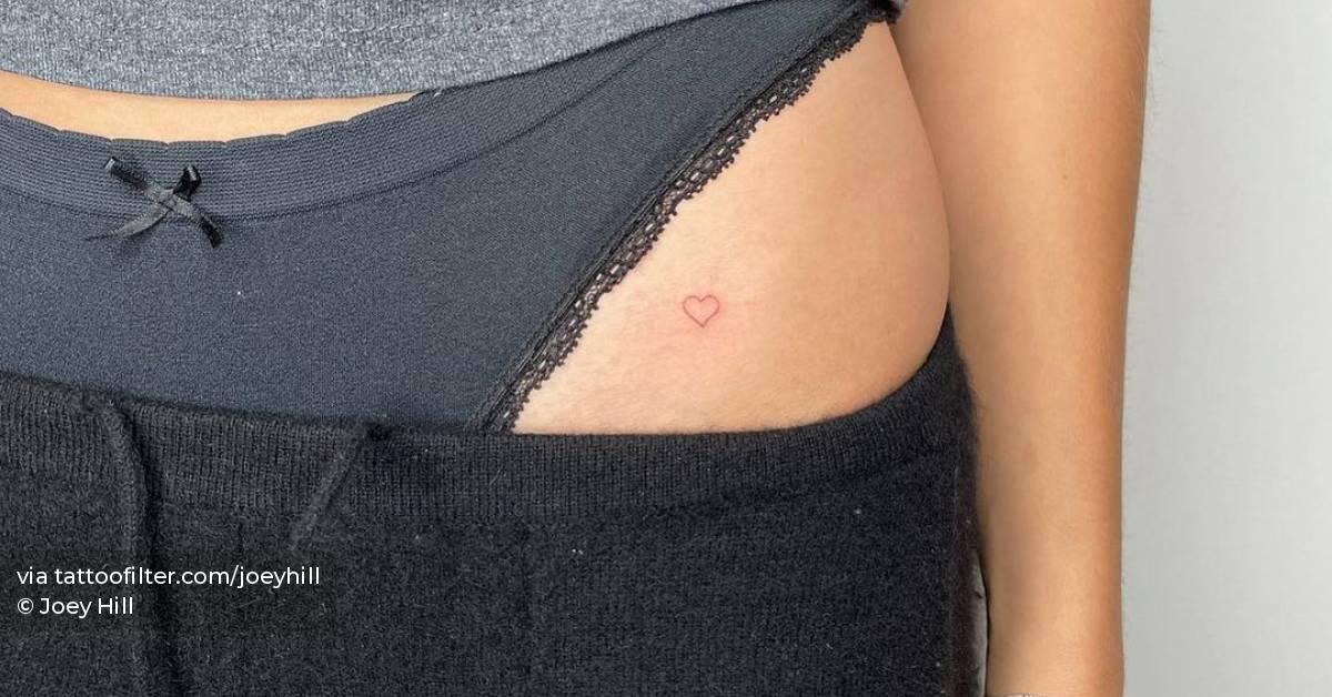 Minimalist red heart tattoo on the pelvis.