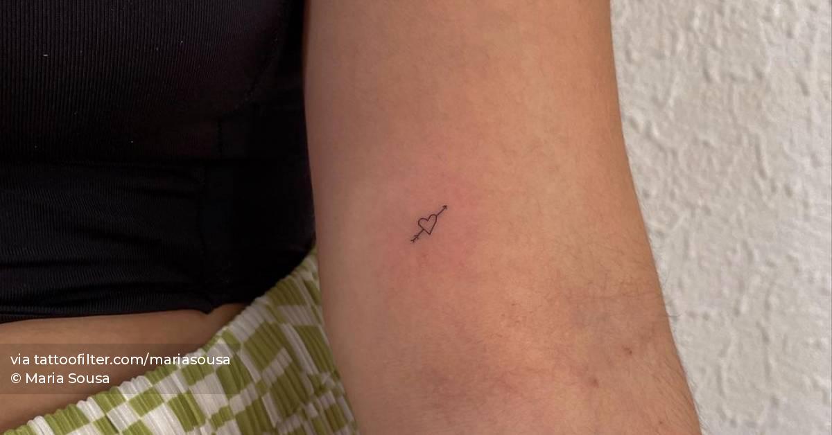 Minimalist heart and arrow tattoo on the inner forearm.