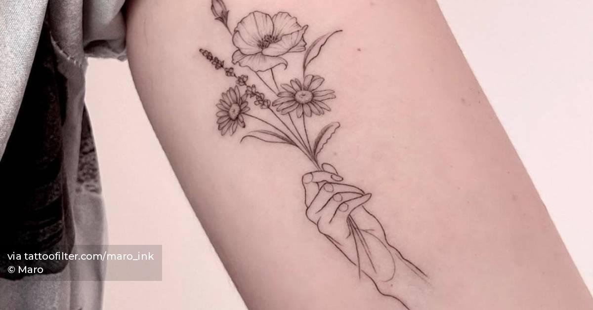 Fine line hand holding flowers tattoo on the inner arm.