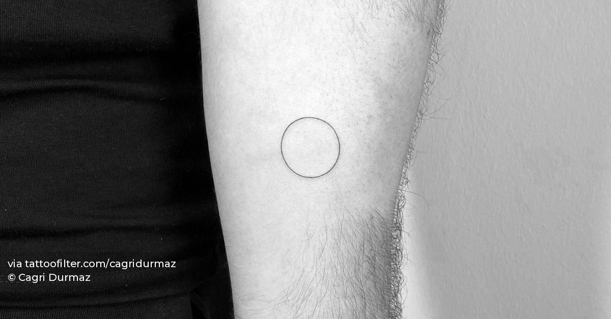 Minimalist circle tattoo on the inner forearm.