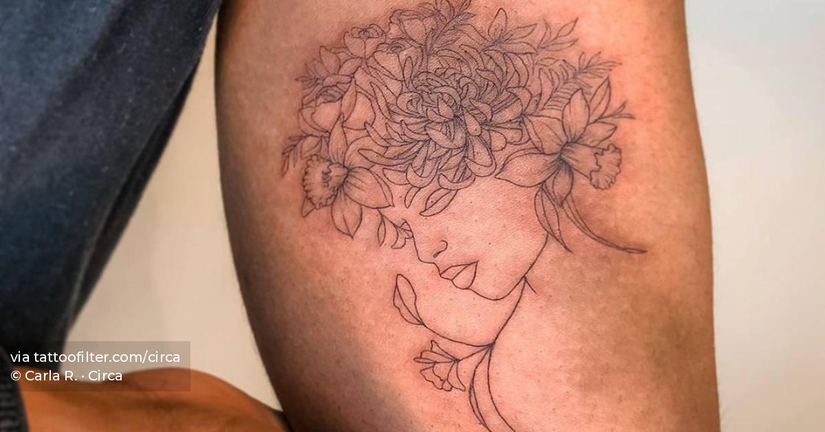 Fine line flower head woman tattoo on the inner arm.