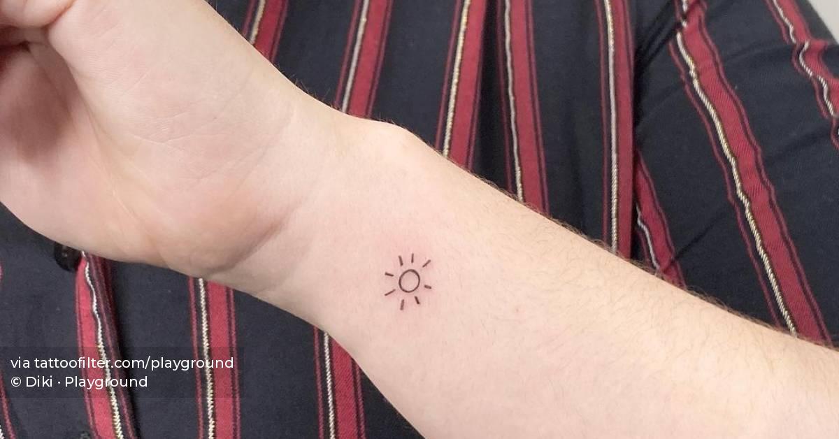 Minimalist sun tattoo on the wrist.