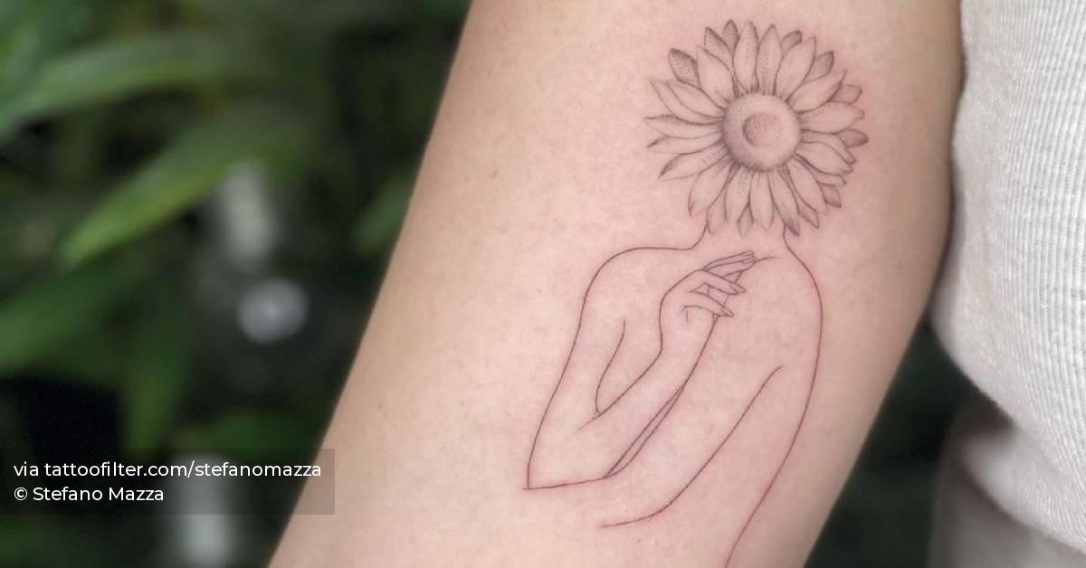 Fine line flower head woman tattoo on the inner arm.