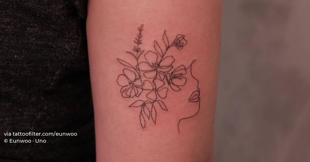 Fine line flower head woman tattoo on the tricep.