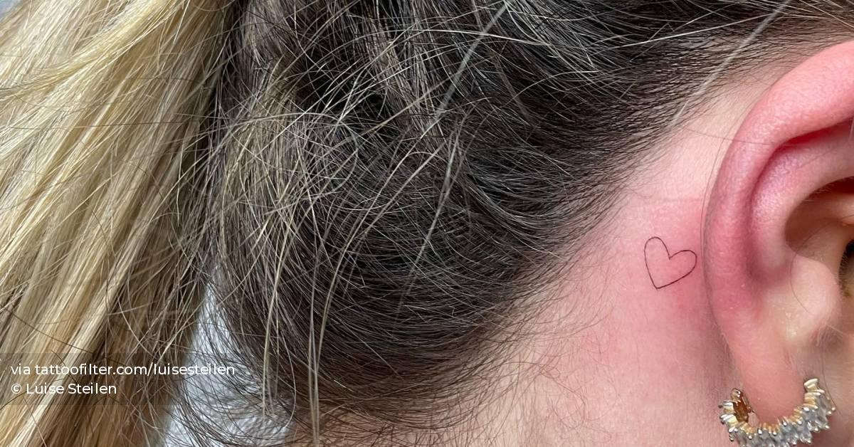 Minimalistic tattoo of a tiny heart located behind the