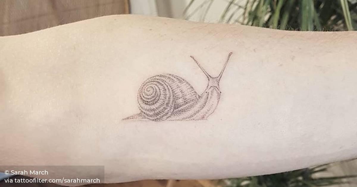 Hand poked snail tattoo on the left inner forearm.