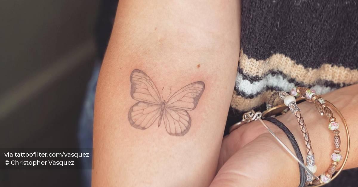 Fine line butterfly tattooed on the inner forearm.