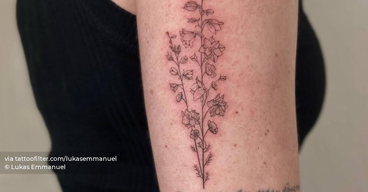 Delphinium tattoo on the upper arm, done in fine line.