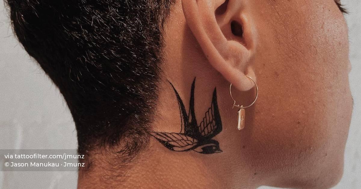 Swallow tattoo located behind the ear.