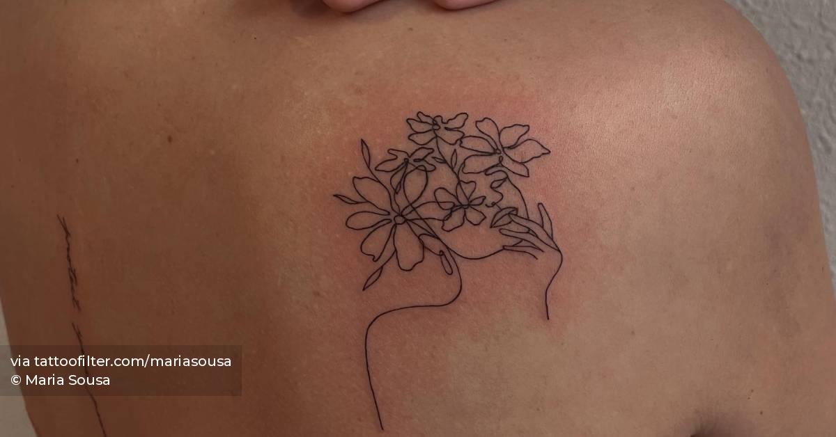 Flower head woman tattoo located on the shoulder blade.