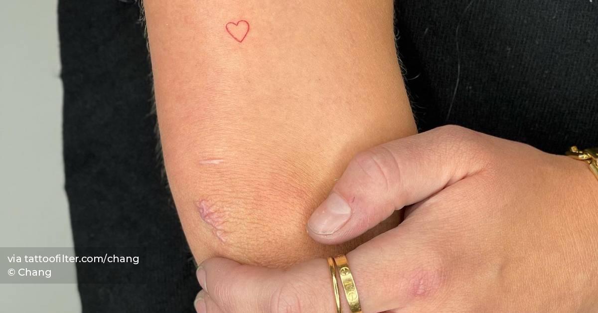 Tiny red heart tattoo located on the tricep,