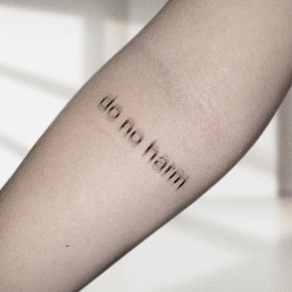 "Do no harm" lettering tattoo located on the inner forearm.