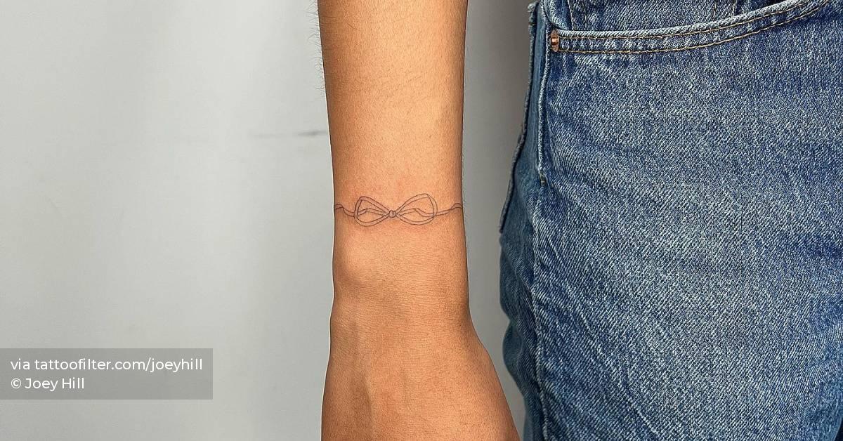 Fine line ribbon wristband tattoo.
