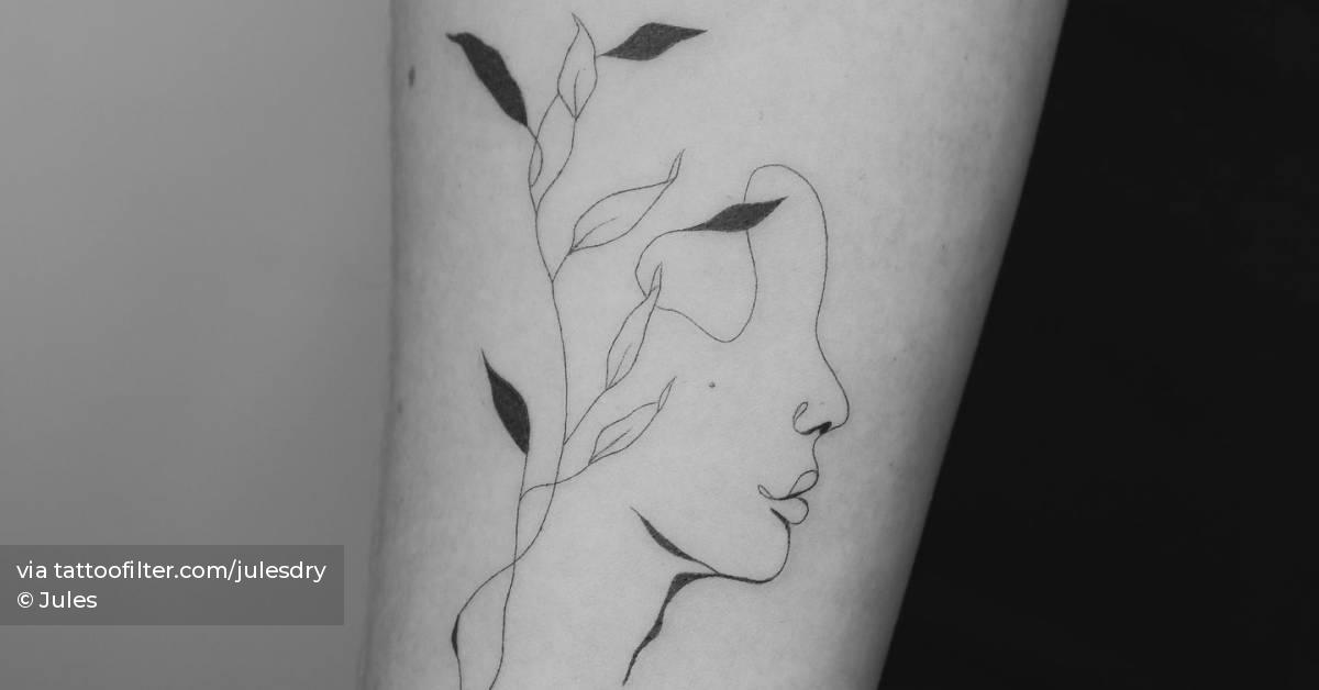 Flower head woman tattoo located on the inner forearm.