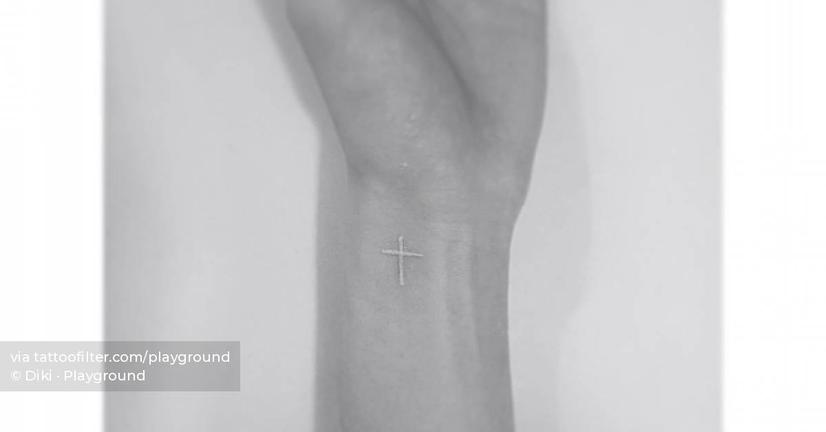Minimalistic cross tattoo done in white ink, located on