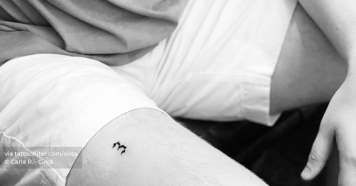 Minimalist number "3" tattoo on the thigh.