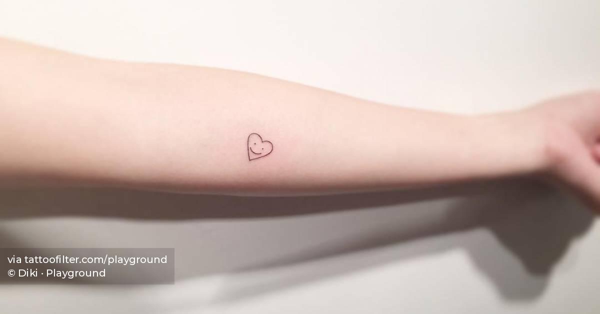 Smiley heart tattoo located on the inner forearm.