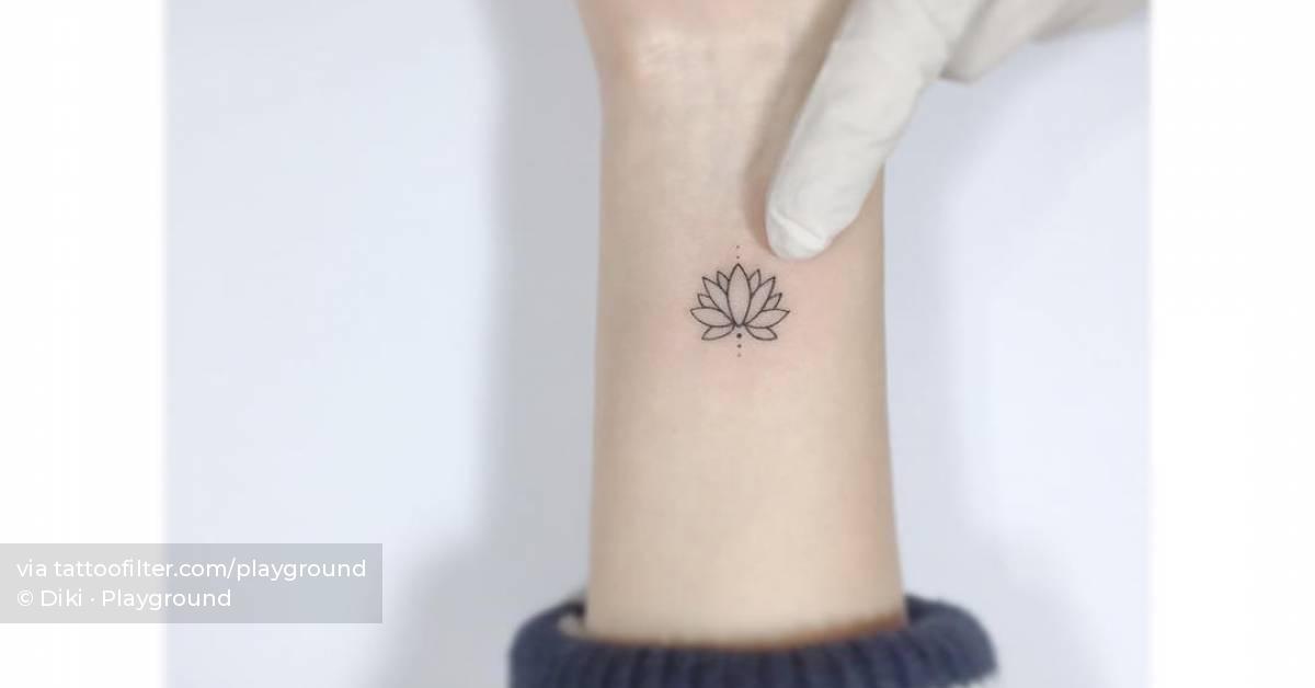 Fine line lotus flower tattoo located on the wrist.