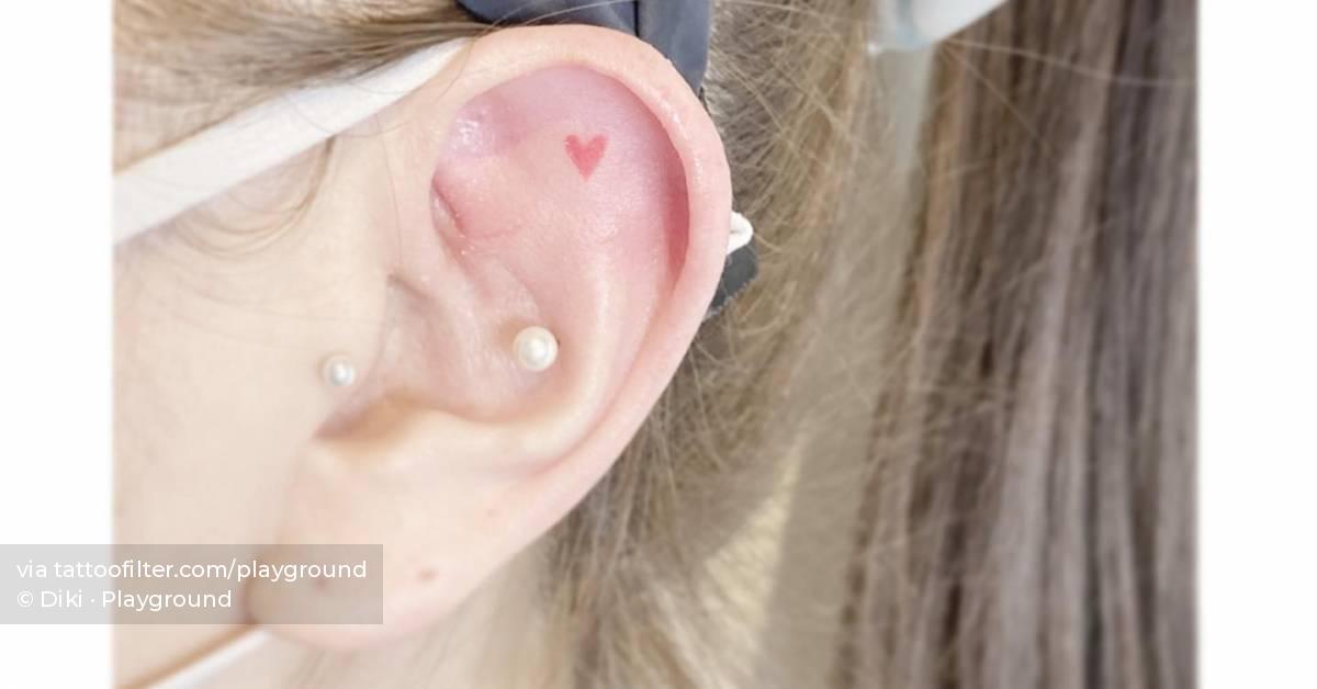 Micro red heart tattooed on the ear, minimalistic