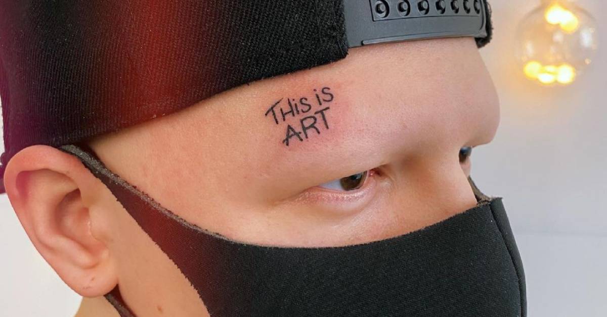 "This is art" lettering tattoo located on the face.