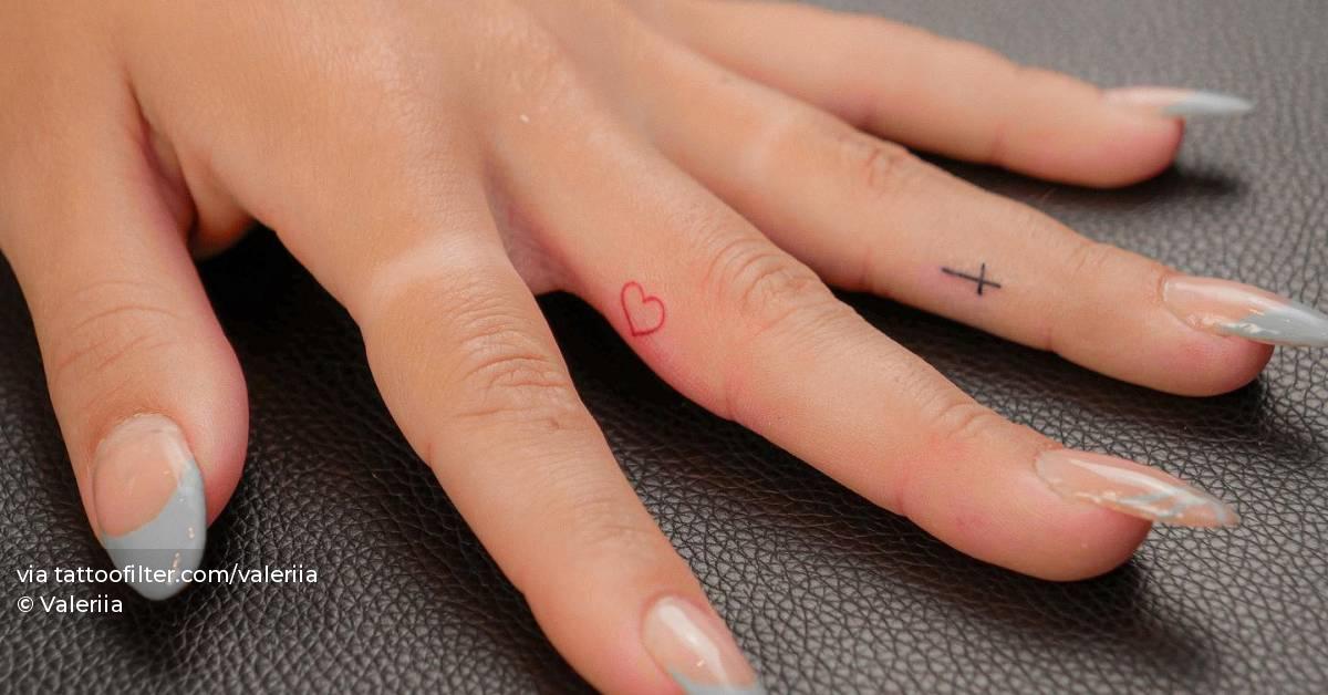 Minimalistic red heart and cross tattoo done on the