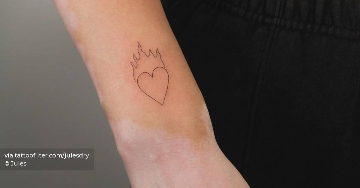 Fine line flaming heart tattoo located on the wrist,