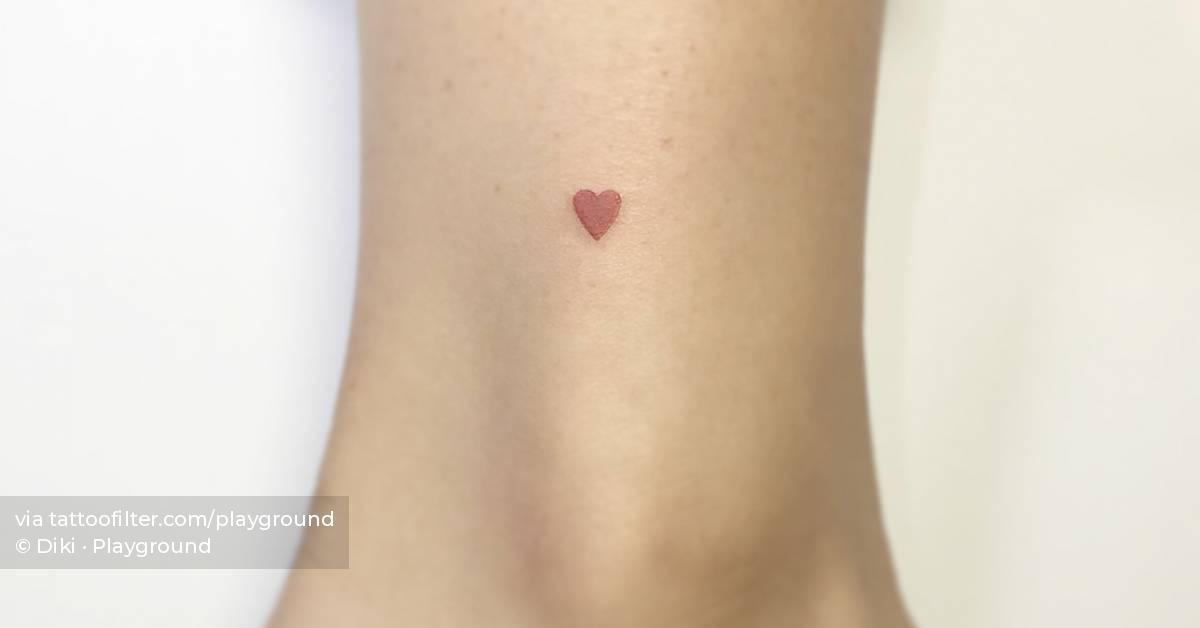 Tiny minimalistic red heart tattoo located on the