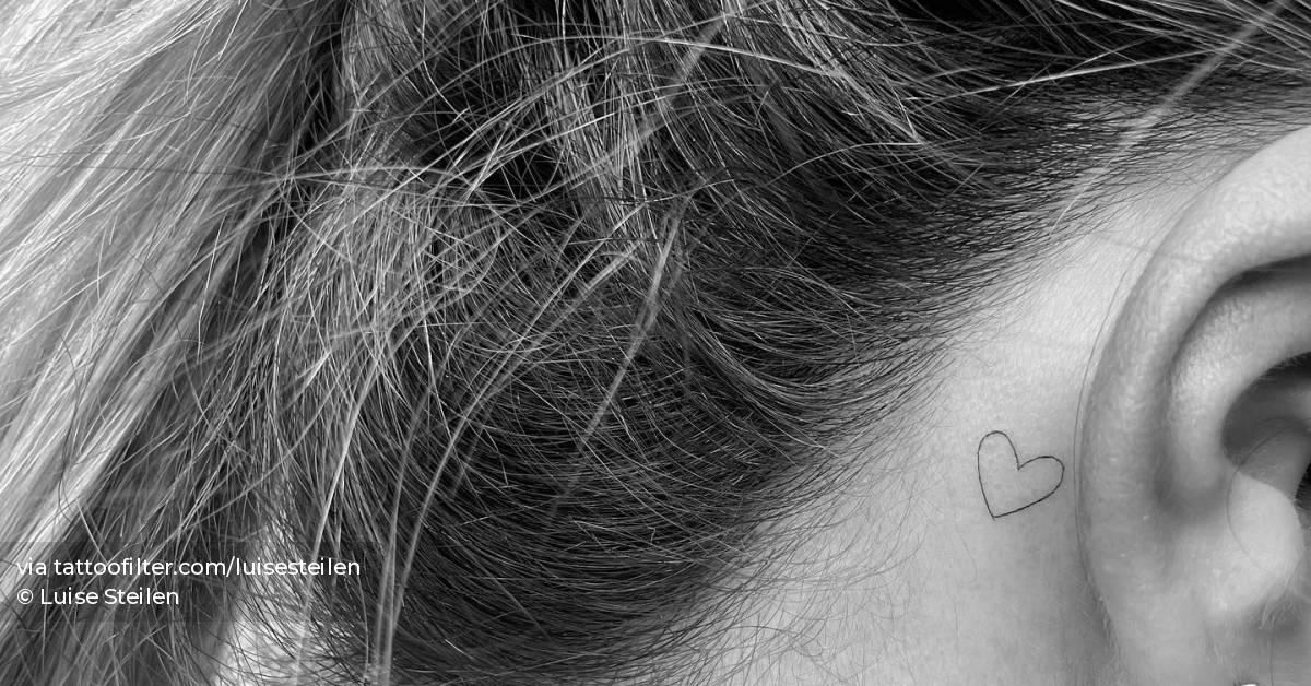 Minimalistic tattoo of a tiny heart located behind the