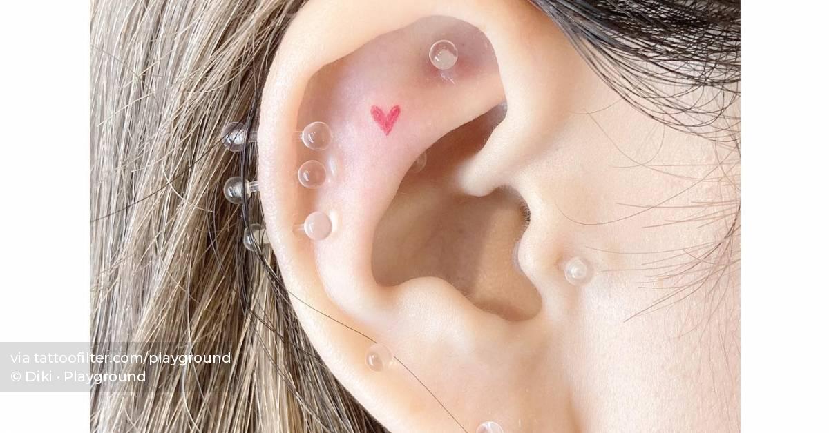 Micro red heart tattoo located on the ear, minimalistic