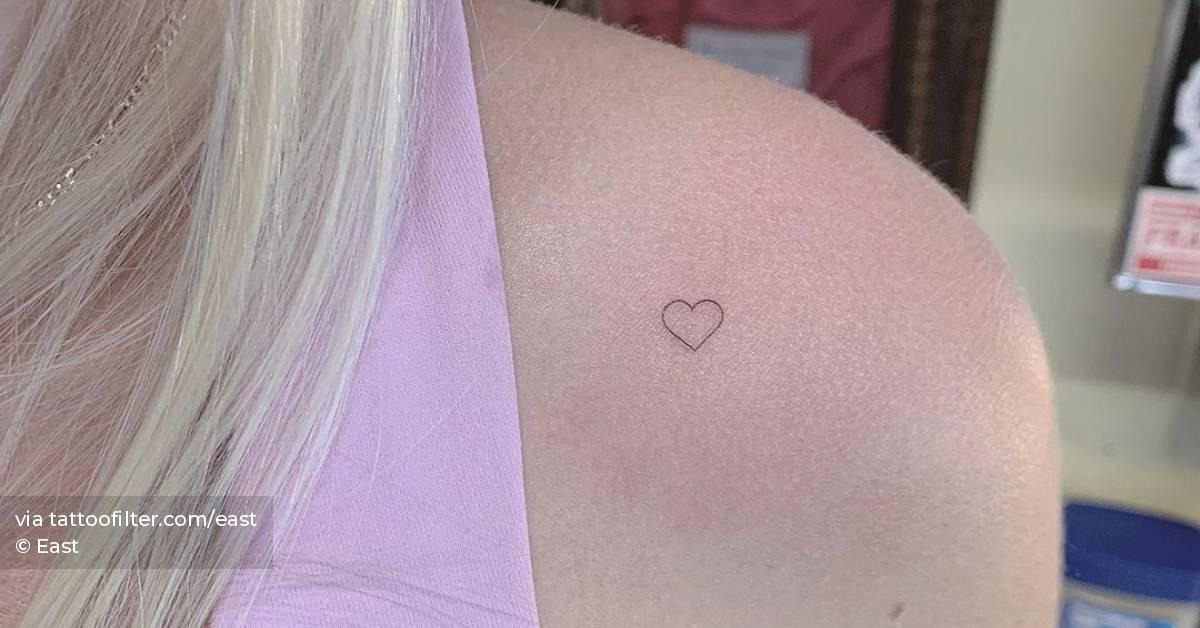 Tiny minimalistic heart tattoo placed on the shoulder.