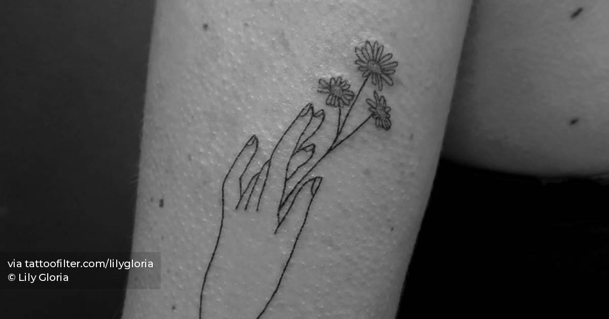Hand poked hand holding flower tattoo located on the